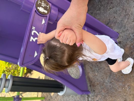 Toddler in front of height requirement signs at attraction