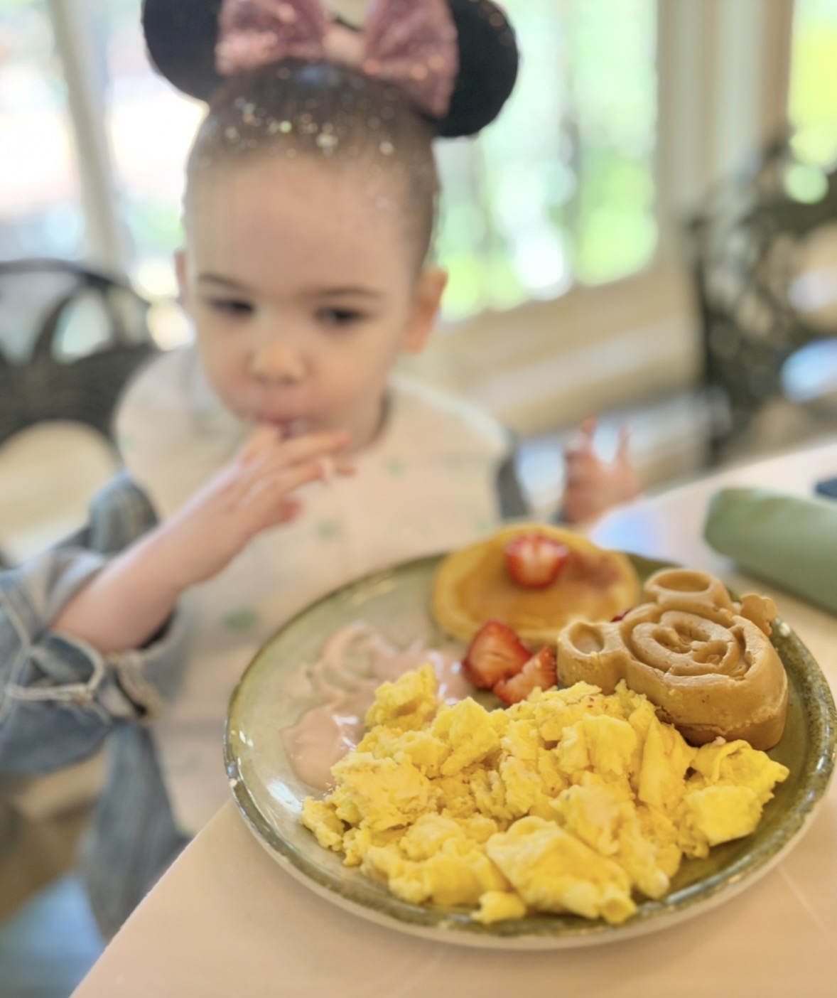 Breakfast plate with Mickey waffle and toddler in background at Walt Disney World