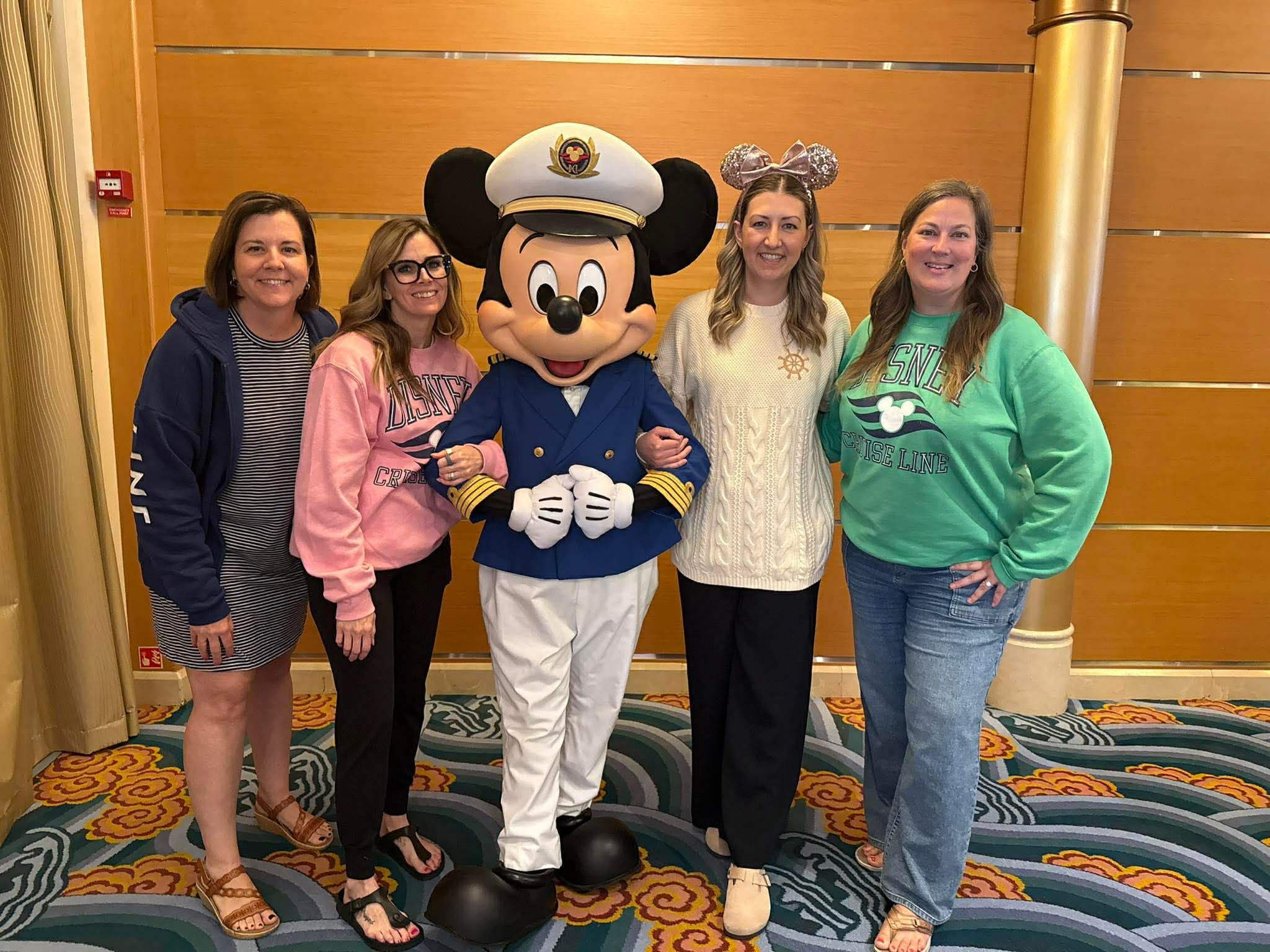 Four Pure Magic Vacations advisors posing with Captain Mickey on the Disney Magic.